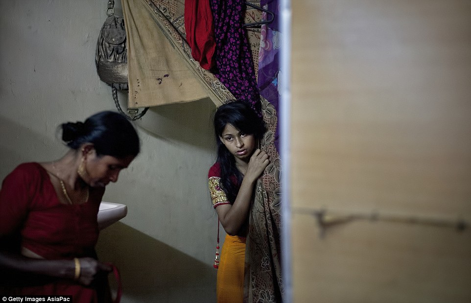 Nervous: Nasoin Akhter looks out of a dressing room at a beauty parlour on the day of her wedding. In Bangladesh, 29 per cent of girls marry before the age of 15 and 65 per cent wed before they turn 18