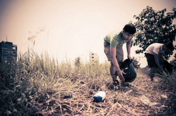 Мужчина собирают мусор на траве