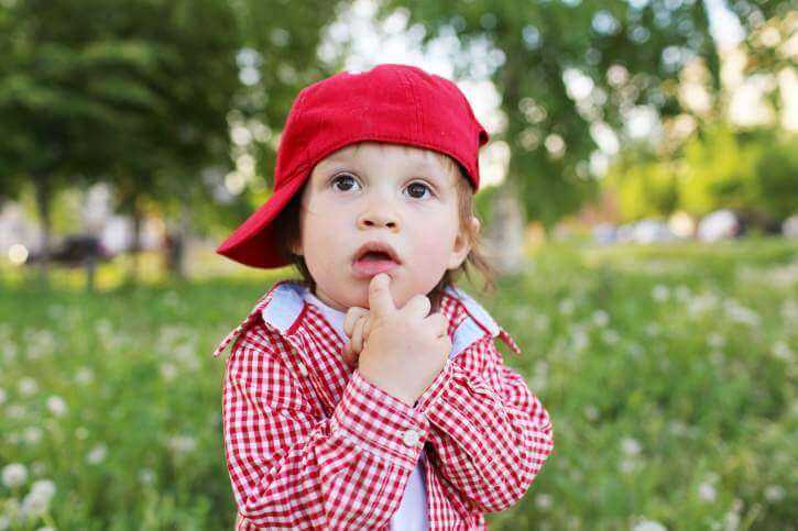 Ребенок на природе в красной кепке задумался