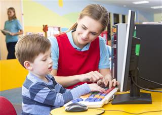 Boy In Front Of Computer With Teacher